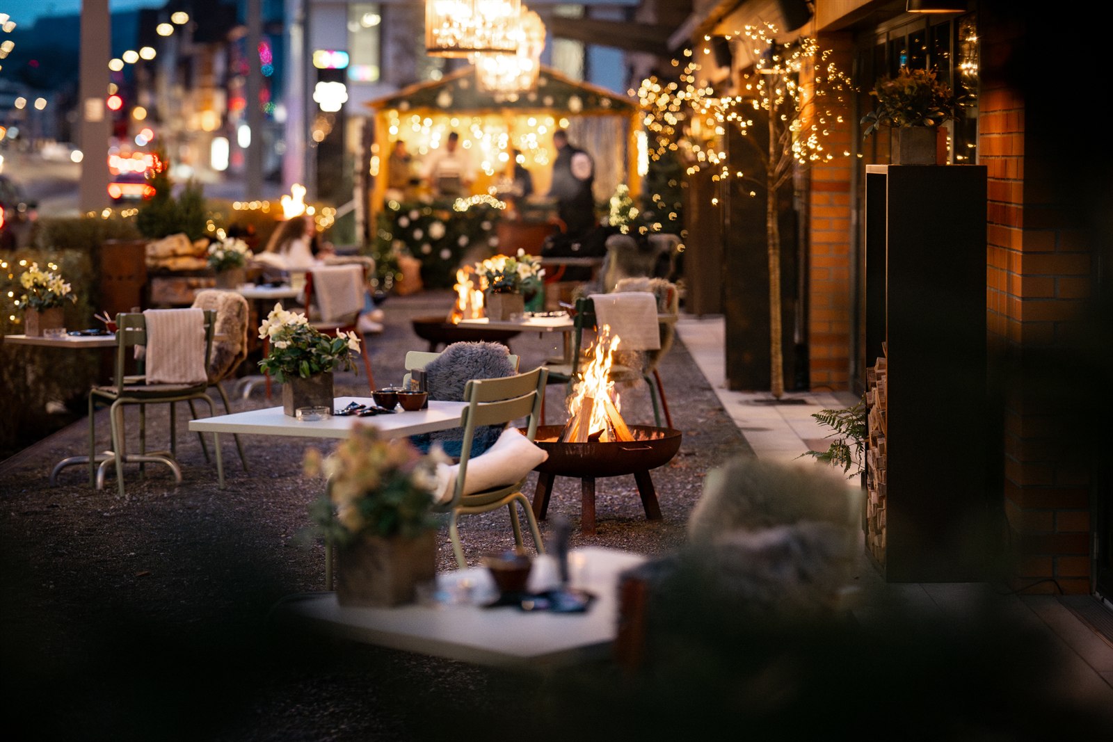 Festlich dekorierte Terrasse mit Feuerschalen, Lichterketten und gedeckten Tischen bei Eve's Kitchen