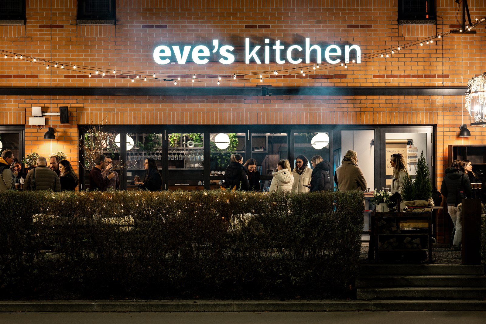 Eve's Kitchen in Schlieren bei Nacht, festlich beleuchtet mit Lichterketten und Gästen beim Weihnachts-Apéro