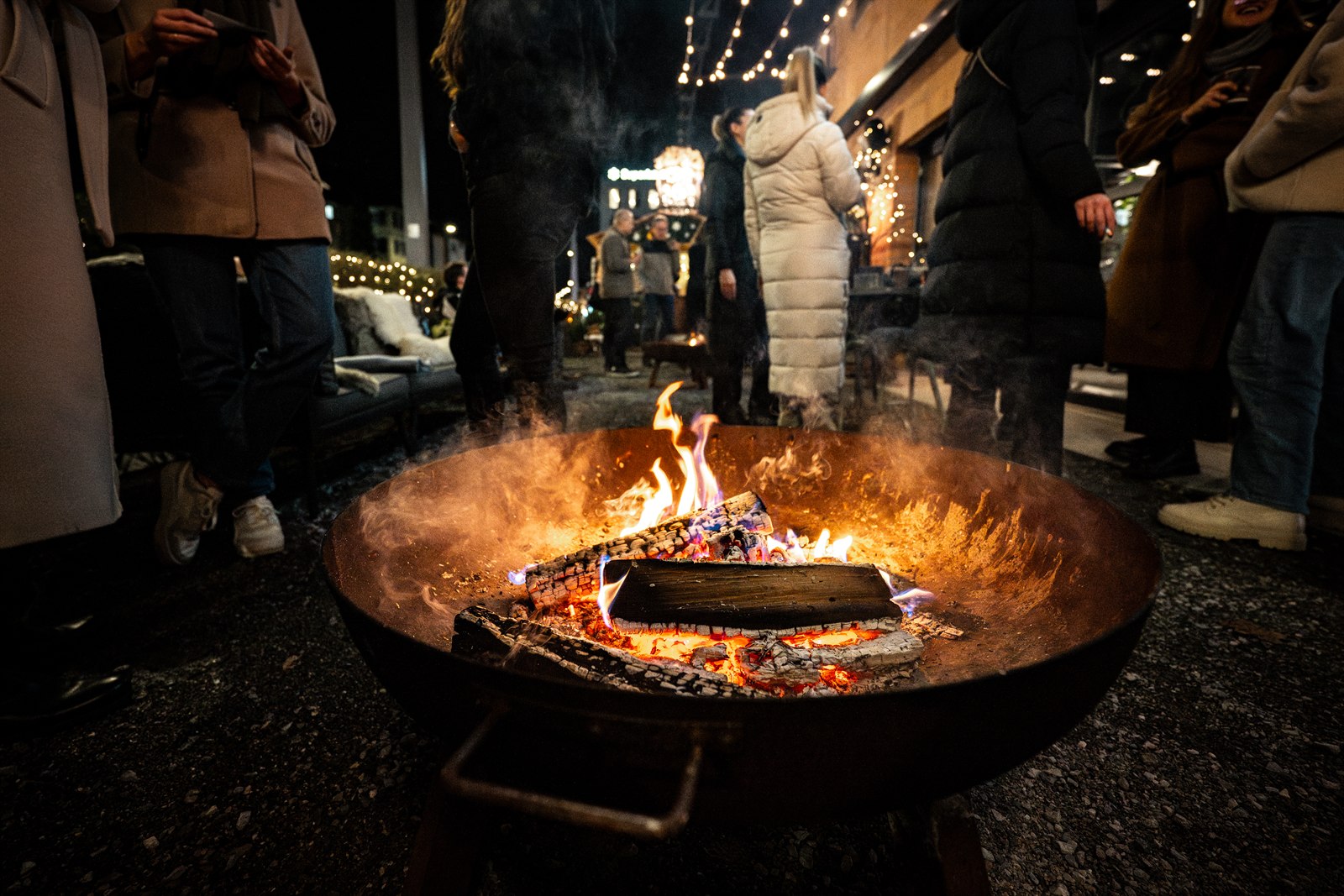 Gäste wärmen sich an der glühenden Feuerschale im Hof von Eve's Kitchen